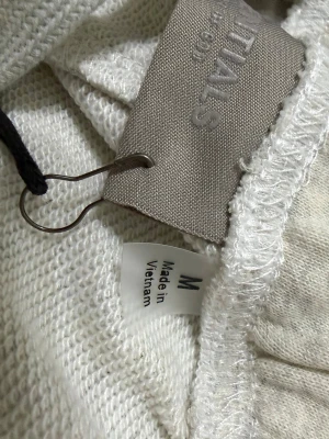 Essentials Fear of God shorts grå M - Snygga ljusgrå shorts från Essentials Fear of God med elastisk midja och logga tryckt på vänster ben. Tillverkade i mjuk bomull som passar perfekt för avslappnade dagar. Klassisk och enkel design som är lätt att matcha.