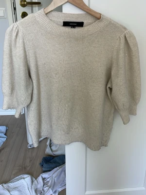 Beige stickad tröja med puffärm - Trendig beige stickad tröja från Vero Moda med puffärmar och rund halsringning. Tröjan har en mjuk struktur och ribbade muddar vid ärmslut och nederkant. Perfekt för dig som gillar en stilren och modern look/stockholm stil