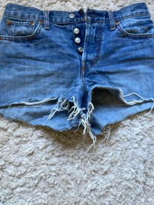 Blå Levis jeansshorts med fransar - Säljer dessa då de blivit för små. De är mid waist/ high waist och sitter jätte snyggt på.