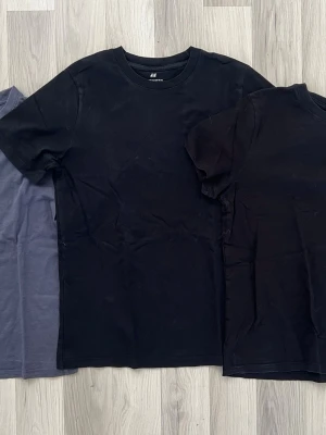 3 tröjor blå, svart, svart - En klassisk svart t-shirt från H&M med rund hals och korta ärmar. Tillverkad i mjuk bomull för en bekväm känsla. Perfekt basplagg som passar till allt och har en normal passform. 150kr för alla 3 och 60kr styck.