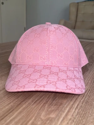 Rosa keps från Zara  med GG-mönster - Säljer en snygg rosa keps från zara med det klassiska GG-monogrammet över hela kepsen. Kepsen har böjd skärm och är tillverkad i ett slitstarkt tygmaterial. Perfekt för dig som vill ha en trendig accessoar med lyxig känsla.