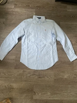 Ljusblå skjorta från Polo Ralph Lauren - Säljer en klassisk ljusblå skjorta från Polo Ralph Lauren med broderad logga på bröstet. Ett parfekt sommar plagg. Storlek M men skulle säga att den sitter som en S 