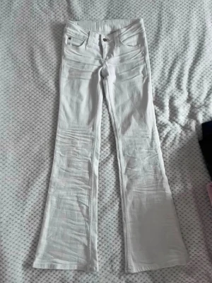 Vita utsvängda jeans från Cheap Monday - Snygga vita jeans från Cheap Monday med utsvängda ben och klassisk femficksmodell. Jeansen har hög midja och en patch med logga bak.