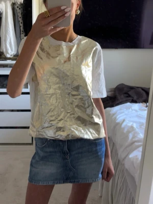 Cool t shirt  - Säljer en vit t-shirt från Zara med ett stort metallic guldtryck på framsidan. T-shirten har klassisk passform och korta ärmar. Perfekt för dig som vill sticka ut med en unik och trendig look. Stl s men är oversized, helt ny! 