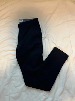 Mörkblå chinos från John Henric - Snygga mörkblå chinos från John Henric med klassisk rak passform. Tillverkade i mjukt bomullstyg med randigt innerfoder i midjan.