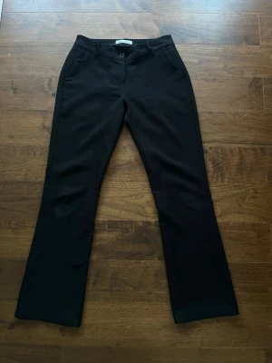 Kostymbyxor - Snygga svarta kostymbyxor från Chelsea i rak/bootcut modell. Byxorna har knapp och dragkedja framtill samt fickor på sidorna. Köpta 2024 men ej använda senaste året pga försmå, är även uppsydda så att de passar någon som är ungefär 160 men går att sprätta upp. 