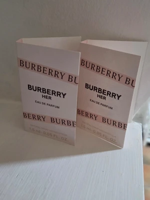 Burberry Her Eau de Parfum 1,5 ml x 2 - Två små provflaskor av Burberry Her Eau de Parfum, 1,5 ml vardera. Parfymen kommer i eleganta vita och rosa kartonger med Burberry-logga. Flaskorna är genomskinliga med vit spraykork och innehåller en ljusrosa doft.