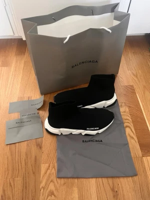  Speed Trainer svarta sneakers - Svarta  Speed Trainer sneakers med vit chunky sula och stickad ovandel i textil. Ikonisk minimalistisk design med logga på sidan och flexibel passform som sitter som en strumpa. Kommer med originalpåse och påsar.
