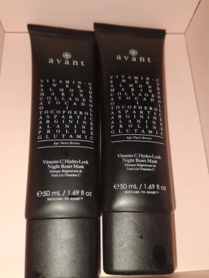 Avant Vitamin C Hydro-Lock Night Mask - Två svarta tuber med Avant Vitamin C Hydro-Lock Night Reset Mask, 50 ml vardera. Ansiktsmasken innehåller vitamin C, kollagen och marina extrakt för återfuktning och lyster. Perfekt för kvällsrutinen och passar alla hudtyper.