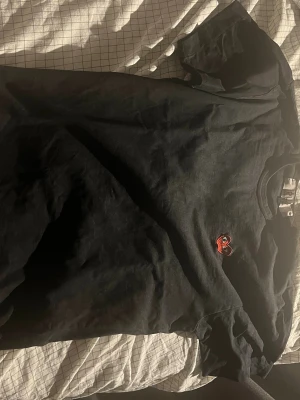 Svart t-shirt från Comme des Garçons - Svart t-shirt från Comme des Garçons PLAY med det ikoniska röda hjärtat broderat på bröstet. Klassisk passform och rund halsringning, perfekt för en clean och stilren look.
