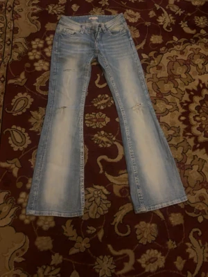 Ljusblå bootcut jeans Gina Tricot - Säljer ett par ljusblå bootcut jeans från Gina Tricot i storlek XS. Jeansen har slitna detaljer på låren och knäna, klassisk femficksmodell och är tillverkade i denim. Perfekta för en trendig och avslappnad look.
