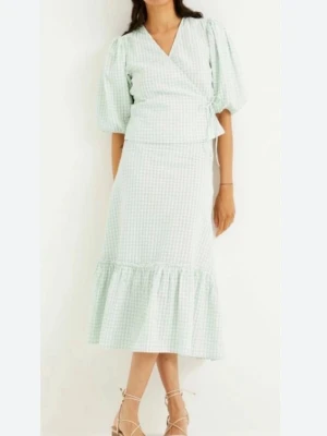 Ljusgrön rutig omlott set från Kappahl storlek S/M - Superfin ljusgrön set med rutigt mönster och puffiga kortärmar. Toppen är en omlottmodell med knyt i midjan i storlek M kjolen är i storlek S men upplever Kappahl lite större i storlek i nederdelar. Perfekt för vår och sommar, tillverkad i mjukt bomullstyg.