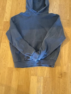 Blå hoodie från Weekday - Säljer en blå hoodie från Weekday i storlek M. Färgen är lite ”washed” och så ska det vara. Riktigt fet! En liten fläck som man kan se på bilden. Inte alls synligt när man använder den.