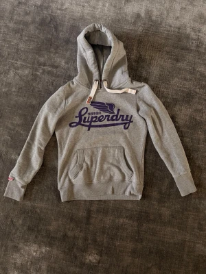 Superdry hoodie - Superdry Hoodie – Trendig & bekväm   Säljer en snygg grå Superdry hoodie med blått tryck framtill. En stilren och populär modell som är perfekt för vardag, skola eller en clean look. Bekväm, mjuk och lätt att matcha med det mesta.  ✨ Märke: Superdry ✨ Färg: Grå med blått tryck ✨ Skick: Fint använt skick ✨ Passform: Bekväm & snygg  Perfekt hoodie för höst/vinter 🍂 Populär modell — först till kvarn! 🚀 Skriv vid intresse eller frågor 📩