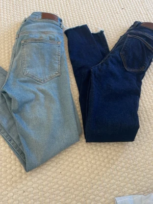 Två par skinny jeans i blå denim - Säljer två par skinny jeans i klassisk denim – ett par i ljusblå tvätt och ett par i mörkblå tvätt. Båda har femficksdesign och läderpatch bak i midjan. Perfekta för dig som gillar en slim fit look och vill ha variation i garderoben.