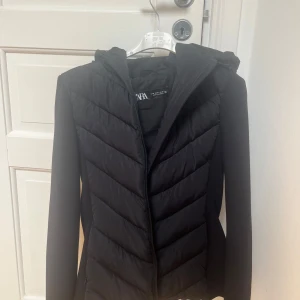 Svart pufferjacka från Zara med huva - Svart pufferjacka från Zara i storlek M. Jackan har en snygg figurnära passform, huva och dragkedja framtill. Oanvänd