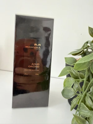 Mancera Aoud Orchid Eau de Parfum - Mancera Aoud Orchid Eau de Parfum i elegant svart och guldig förpackning. Flaskan rymmer 120 ml och doften kombinerar lyxiga noter av oud och orkidé. Perfekt för dig som gillar exklusiva och unika parfymer med en orientalisk touch.