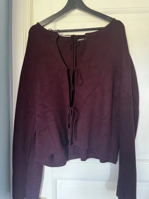 Vinröd stickad tröja med knytning - En stickad tröja med knytning, en tröja från Gina, använd få gånger, storlek L. Alla kläder tvättas innan.