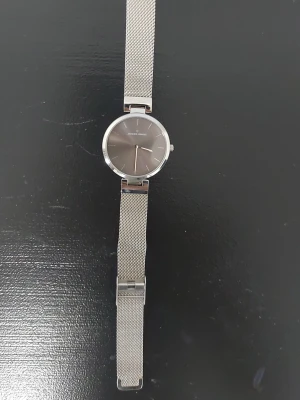 Silverfärgad klocka från Daniel Wellington - Stilren klocka från Jacques Lemans med mesh-armband i silverfärgat rostfritt stål. Urtavlan är rund och minimalistisk med silverdetaljer. Perfekt accessoar för dig som gillar en clean och modern look.
