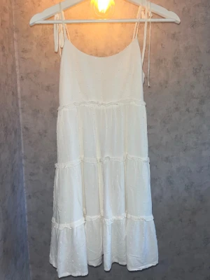 Vit sommar klänning🎀 - Jätte fin vit klänning med smala axelband som knyts på axlarna. Klänningen har volangdetaljer och är i storlek xs💞