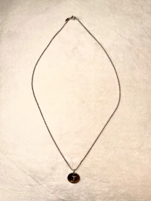 OWN IT halsband - Guldfynd by Bianca - Snyggt halsband i 925 sterlingsilver med en rund bricka som har ett ingraverat T och tunn kedja. Köpt från ett samarbete mellan Guldfynd och Bianca Ingrosso 🤍🤍 Berlocken är lite ärjad men det går nog att fixa med silverputs - Billigare vid snabb affär - skicka ett prisförslag! 