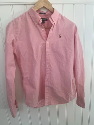 Polo skjorta - Snygg rosa ralph lauren skjorta, perfekt nu till sommaren, Storlek 4, motsvarar ungefär xs, jätte bra skick, skriv ifall ni har några funderingar!