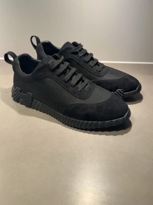 Svarta sneakers med chunky sula - Stilrena helsvarta sneakers med grov, räfflad sula och ovandel i textil och mockaimitation. Skorna har lågt skaft, klassisk snörning och dragflik bak. Perfekta för en clean och modern look.