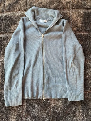 Grå ribbad ziptröja från Ljung - Snygg grå ziptröja från Ljung Marcus Larsson i ribbat material. Tröjan har hög krage, hel dragkedja framtill och långa ärmar. Perfekt för lager på lager och enkel att matcha med olika outfits. Nypris 2700 står XL med sitter mer som L