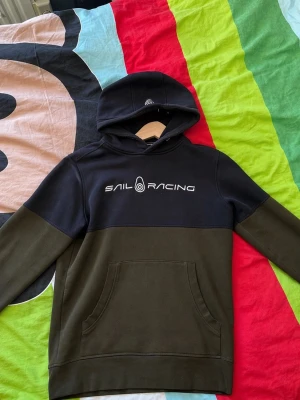 Sail Racing hoodie i svart och olivgrön - Snygg hoodie från Sail Racing i svart och olivgrönt. Tröjan är i mycket bra skick, billigare pris fungerar vid smidig affär🙌