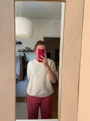 Kortärmad oversized tröja - Säljer en enkel och stilren vit stickad tröja med korta ärmar och rund hals. Tröjan har en avslappnad passform och ribbade kanter nedtill och vid ärmsluten