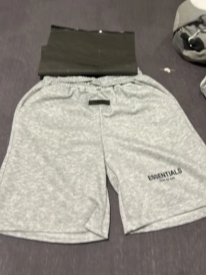 Grå shorts från Essentials - Snygga ljusgrå shorts från Essentials med elastisk midja och diskret logga på benet. Tillverkade i mjukt material som känns skönt mot huden. Perfekta för chill eller träning. Klassisk passform och enkel design.