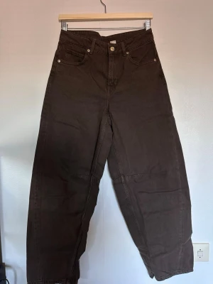 Bruna wide leg jeans med hög midja - Säljer ett par bruna jeans med hög midja och wide leg-passform. Jeansen har klassiska fem fickor och raka ben. Perfekta för dig som gillar en avslappnad och trendig stil. Materialet är kraftigt och slitstarkt, vilket ger en cool look.
