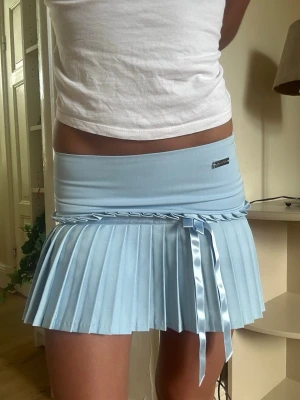 Helt ny La petite française minikjol - ❣️Kostade mellan 5-800 nypris❣️Ny utan prislapp!! Supersöt ljusblå kort kjol med plisserad design och bred midjeresår från La petite française!! Kjolen har en liten volangdetalj upptill och är gjord i ett glansigt, stretchigt material som ger en sportig vibe. Perfekt för dig som vill sticka ut med en trendig och lekfull look.