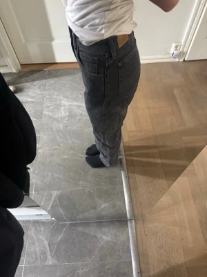 Svarta raka jeans från Levi's - Säljer ett par svarta raka jeans från Levi's med klassisk femficksmodell och hög midja. Jeansen har en enkel knappstängning och bälteshällor. Perfekta för dig som gillar en tidlös och avslappnad stil.