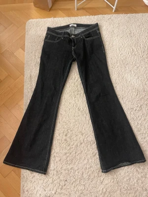 Mörkblå  bootcut jeans med vita sömmar gina tricot  - Snygga mörkblå  bootcut jeans med kontrasterande vita sömmar och klassiska fem fickor. Jeansen har låg midja och utsvängda ben, från gina tricot , midjemått 41, innerbenslängd:81, midjehöjd:20 
