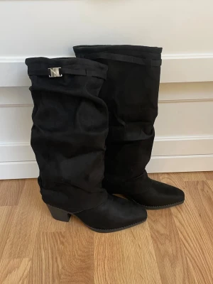 Svarta höga stövlar med klack - Säljer ett par svarta höga stövlar. Stövlarna är tillverkade i mocka och har en slouchy design. Aldrig använda då de var i för liten storlek💕