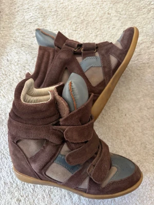 Bruna Isabel Marant Sneakers - Bruna sneakers i mocka och skinn med högt skaft. Det är brun med grå detaljer.Perfent till sommaren, storlek 38.