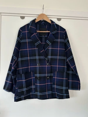Blårutig oversized kavaj - MONKI - XS - Superfin blå rutig kavaj / blazer / jacka från Monki i storlek XS (är oversize-modell så passar även S om man gillar mer figurnära). Kavajen har en klassisk dubbelknäppt design med svarta knappar och två fickor framtill. Mönstret består av en djup bas i mörkblått / navy med rutiga ränder i ljusblått och rosa. Superhärligt kavaj som passar till de flesta outfits. Mycket gott skick, som ny!