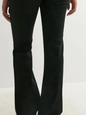 Svarta bootcut jeans från Nelly - Säljer ett par svarta bootcut jeans från Nelly med klassiska bakfickor och broderad detalj. Jeansen har normal passform upptill och utsvängda ben. Storlek 36 short