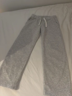 Grå mjukisbyxor från russemerch XS - Säljer ett par ljusgrå mjukisbyxor från Russemerch i storlek XS. Byxorna har raka ben, resår i midjan med vit dragsko och är gjorda i mjukt sweatshirtmaterial. Perfekta för chill dagar eller när du vill vara extra bekväm.