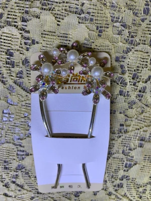 Hårspänne med pärlor och strass - Snyggt hårspänne i metall med två stora blommor dekorerade med vita pärlor och lila strasstenar. Blommorna har en glittrig och elegant look som verkligen sticker ut i håret. Perfekt accessoar för att ge frisyren extra bling och stil.