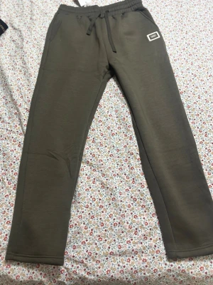Olivgröna mjukisbyxor från H&M - Snygga olivgröna mjukisbyxor från H&M med dragsko i midjan och resår. Två sidofickor fram och en bakficka. Raka ben och mjukt material som känns skönt mot huden. Perfekta för chill eller streetwear.