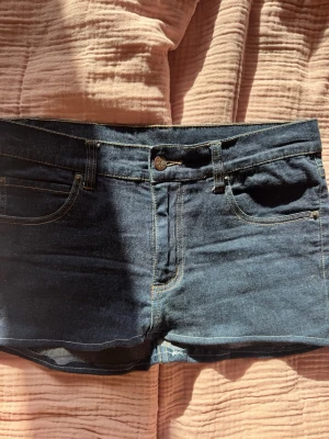 Mörkblå jeansshorts med fem fickor - Snygga mörkblå jeansshorts med klassisk femficksdesign och gul kontrastsöm. Shortsen har knapp och dragkedja framtill samt rå kant nedtill för en avslappnad look. Perfekta till sommaren och lätta att matcha med olika stilar.sytt om själv 💓