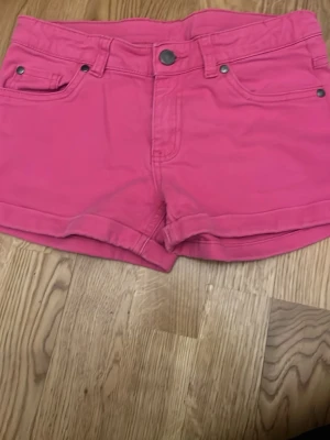Rosa shorts med fickor - Snygga rosa shorts med fem fickor och bälteshällor. Klassisk knappstängning framtill och broderad detalj på ena bakfickan. Perfekta för varma dagar och har en normal passform.