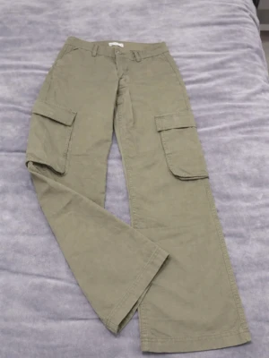 Beiga cargobyxor med stora fickor - Säljer ett par beiga cargobyxor med bred passform och stora sidofickor med lock. Byxorna har hällor för skärp och raka ben. Perfekta för en avslappnad och trendig look. Materialet känns slitstarkt och passar till streetwear-stil.