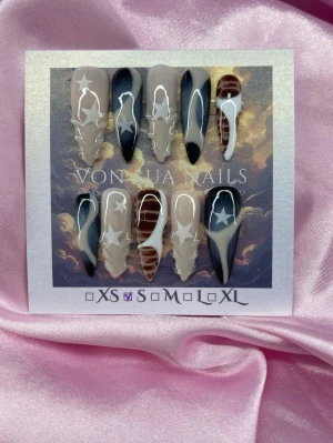 Archive 2.0 (S);Long Stiletto - Unika handgjorda press-on naglar i svart, beige och vitt. Mixade designer med stjärnor, Y2k linjer och coola detaljer. Långa, spetsiga tippar i S: 15 mm, 11,5 mm, 12 mm, 11 mm, 9 mm, som ger en edgy look. Perfekt för dig som vill sticka ut med unika naglar.