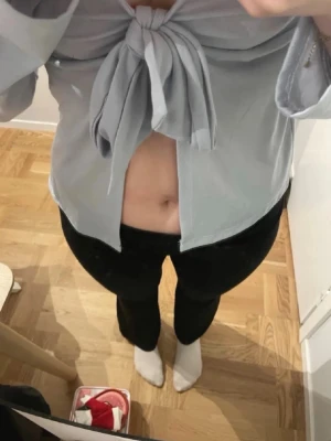 Ljusblå knytblus från Gina Tricot - Trendig ljusblå blus från Gina Tricot med stor knytning framtill. Blusen har långa ärmar och croppad passform som visar magen. Perfekt för dig som vill ha en cool och modern look.