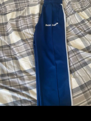 Palm Angels byxor  - Säljer ett par blåa mjukisbyxor från Palm Angels då jag har ledsnat på dem. Fint skicka då dom är använda sparsamt. 
