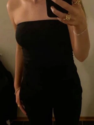 Svart tubtopp - Snygg svart tubtopp. Toppen har en onsynlig dragkedja i ryggen och silikon kant på insidan så att den inte glider ner. Fint sick! 