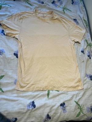 Beige kortärmad t-shirt - En enkel beige t-shirt med rund hals och korta ärmar. T-shirten har en klassisk passform och är tillverkad i mjukt bomullsmaterial. Perfekt basplagg för alla tillfällen.